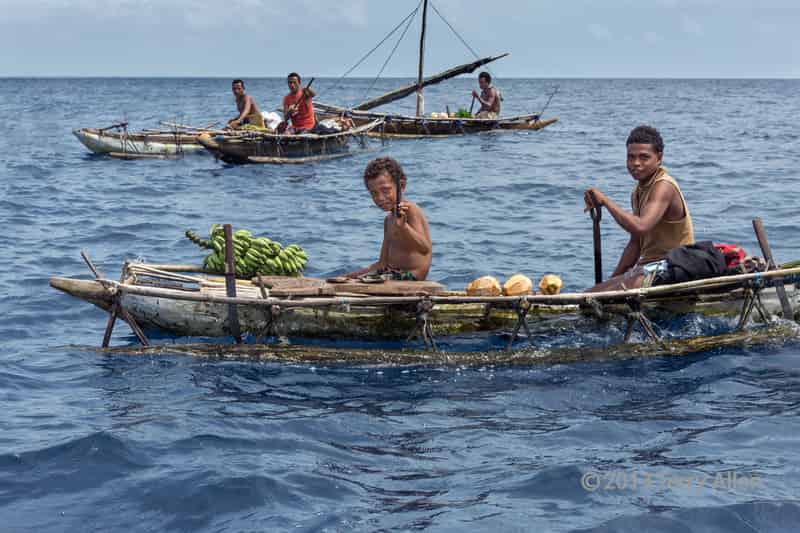 Boys in outrigger canoe selling coconuts