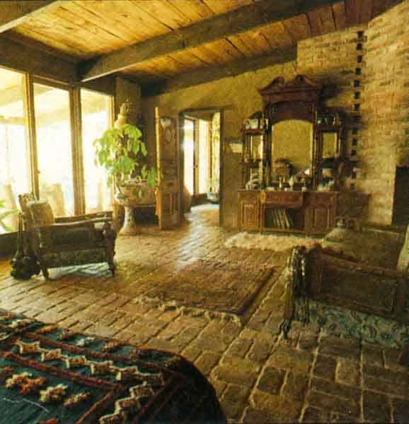 The main bedroom is large and open, with its own fireplace and sitting area. C. A bright Afghani rug on the bed stands out against the earth-colored walls.