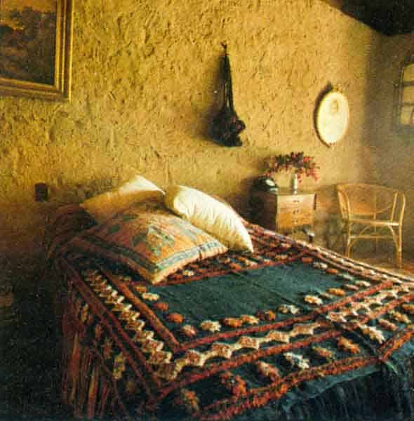 A bright Afghani rug on the bed stands out against the earth-colored walls.