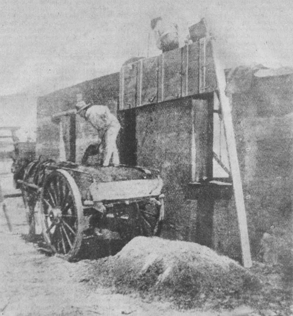 Pioneer pise, showing form work box and soil being shovelled from a horse and cart.