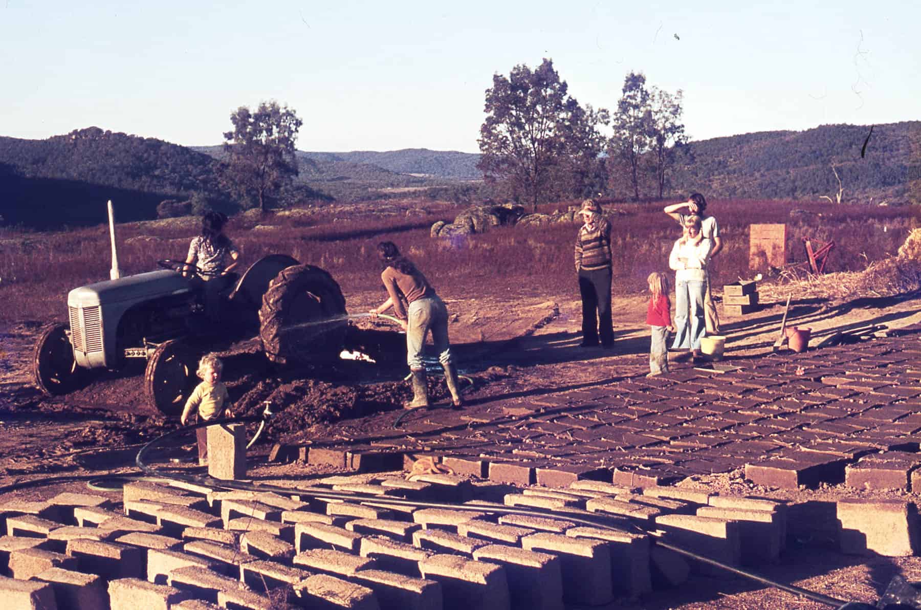 A mud brick idyll - Esther Rodenstock drives the tractor and Helen Hyatt wets the soil, while the author and the Rodenstock children supervise. The Woolshed Valley lies in the distance